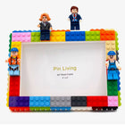 Colorful DIY photo frame made of interlocking bricks with small figures on a white background.